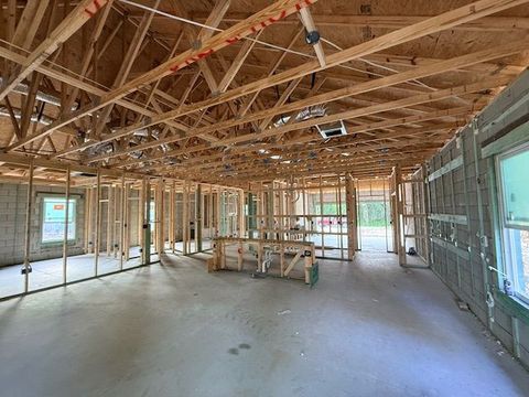 Empty house under construction with exposed wooden roof trusses and unfinished walls