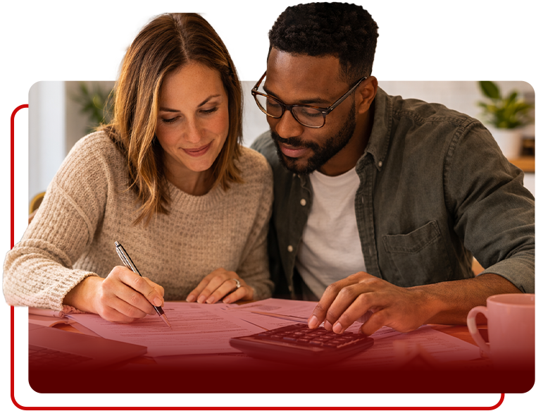 A person writing on a document while another person uses a calculator at a table, suggesting financial planning.