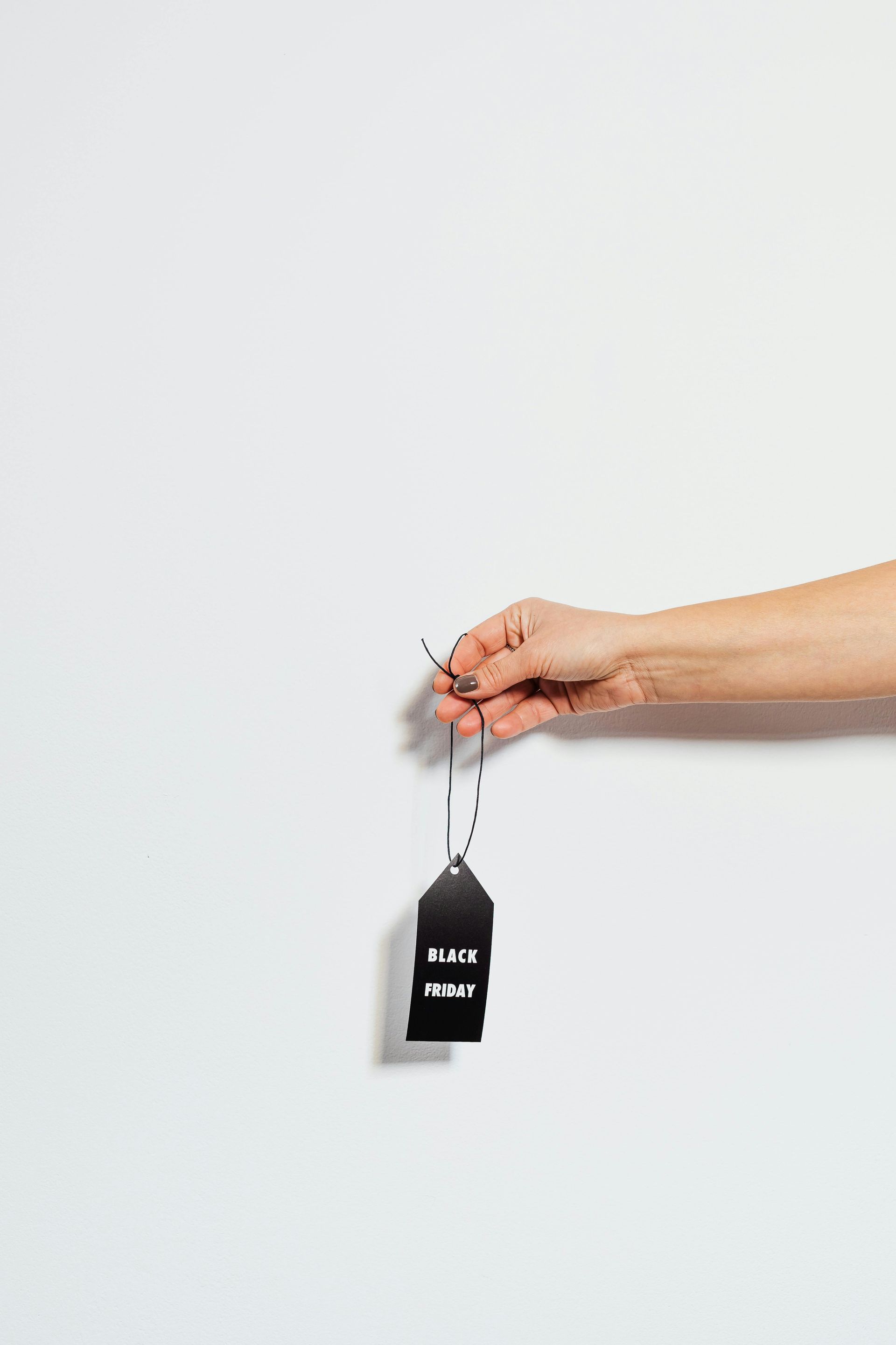 Hand holding a black tag against a white background; tag reads