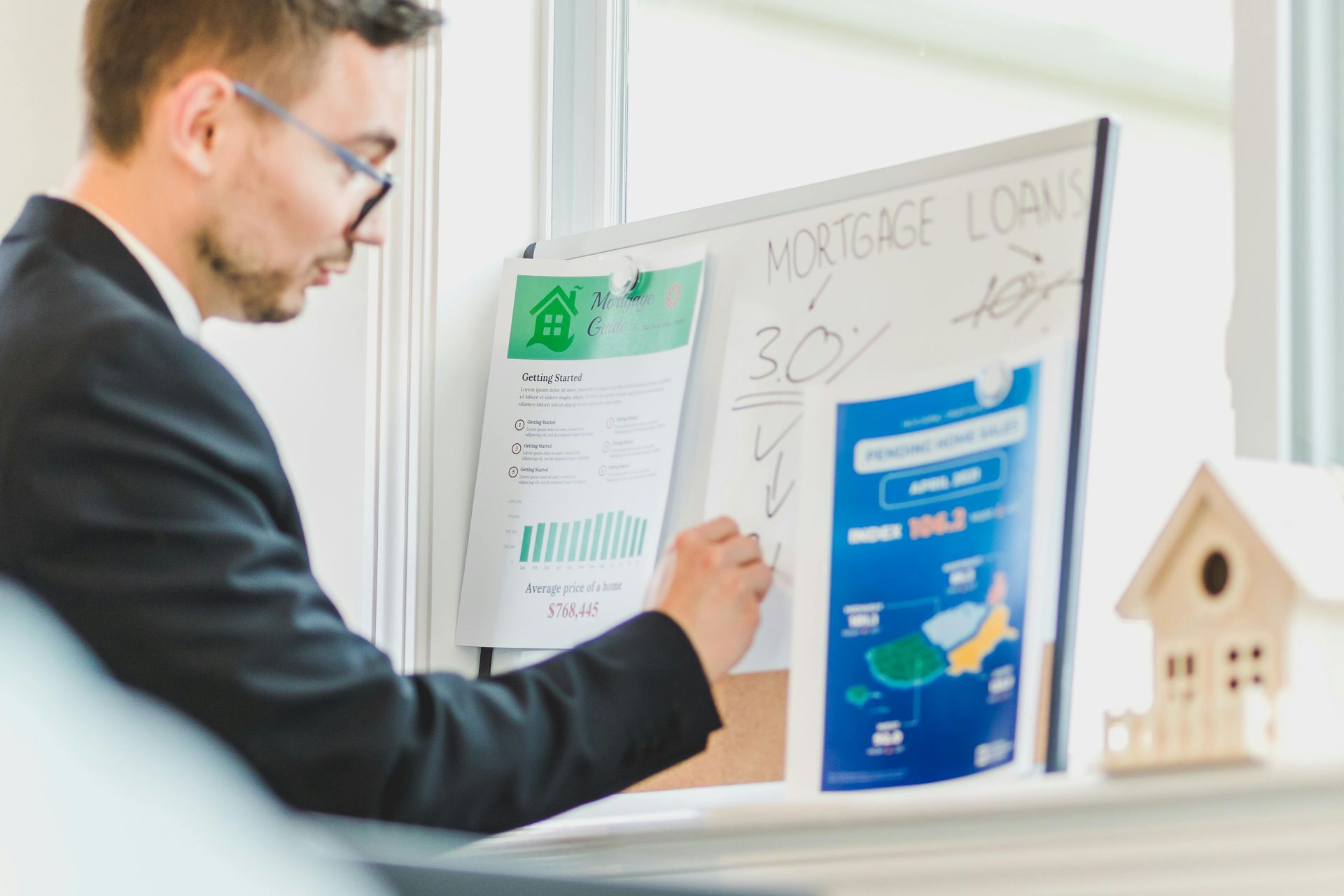 Man in suit analyzing mortgage loan details on a whiteboard near a window.
