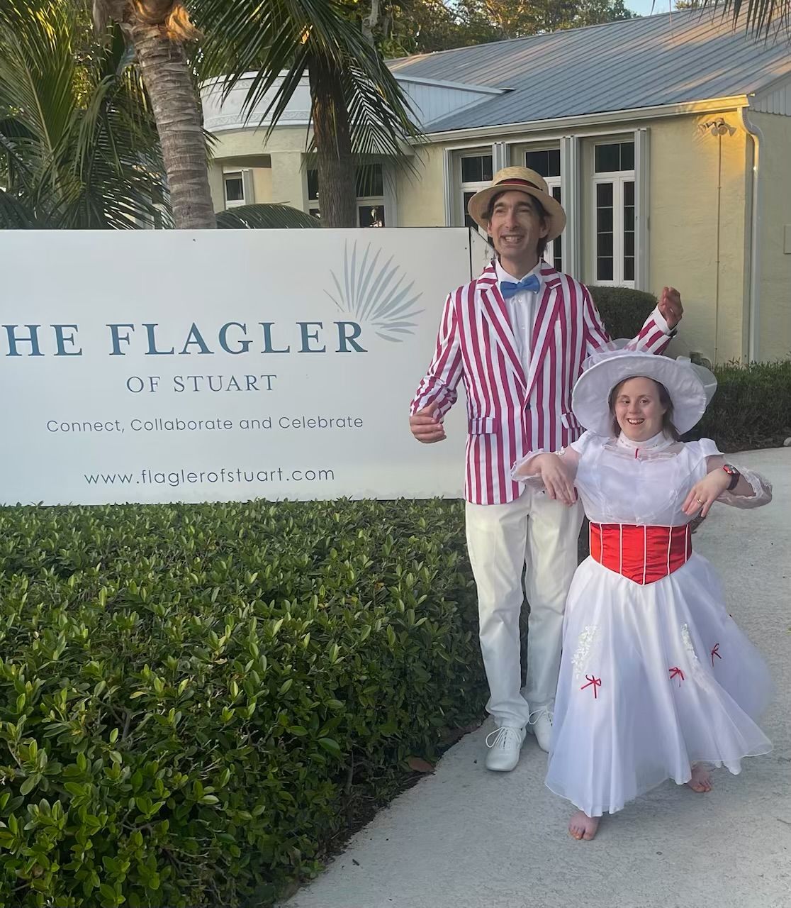 Two people in red-and-white costumes posing beside a 
