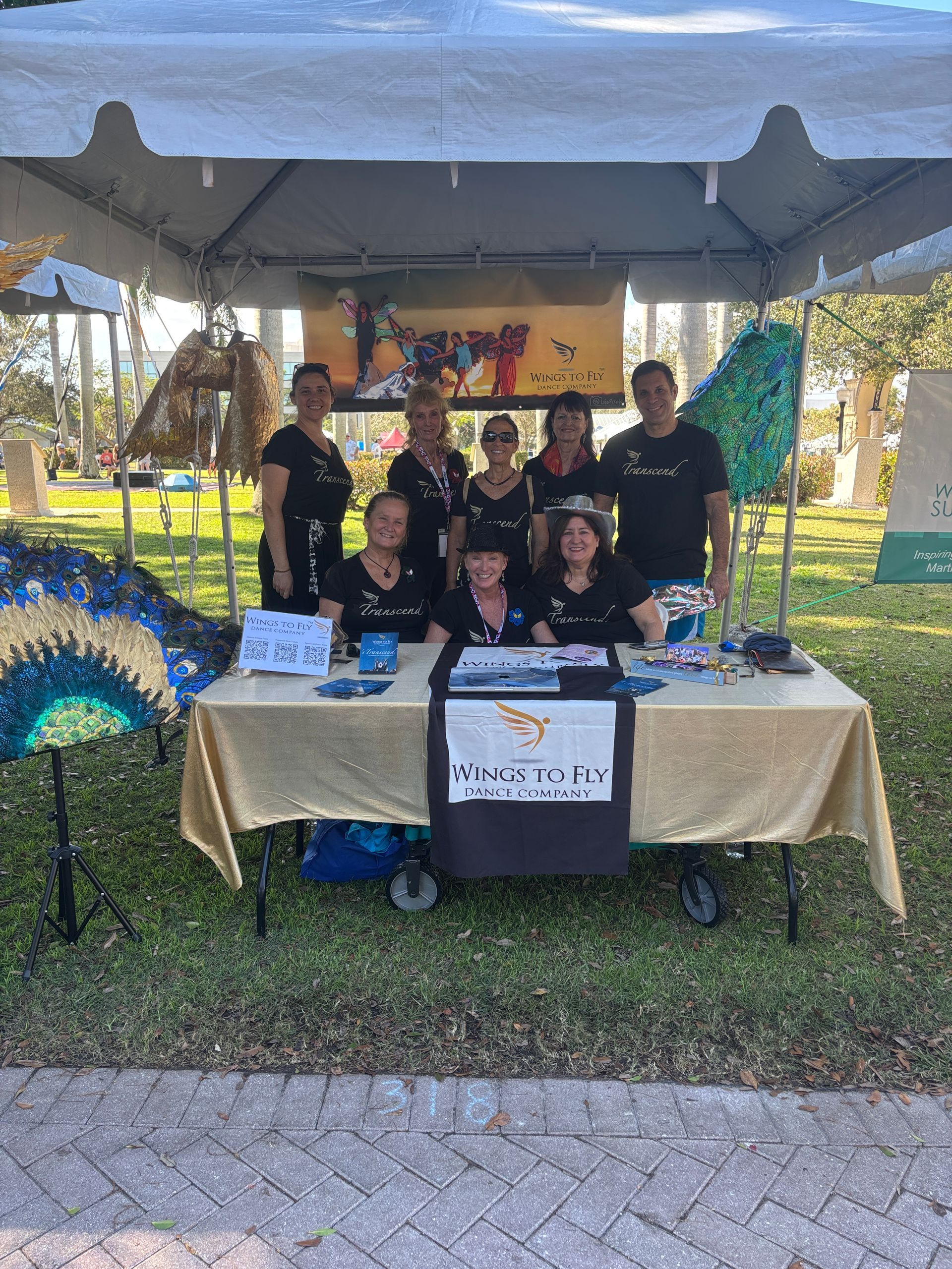 Group at a canopy booth with a table display and banner at an outdoor event