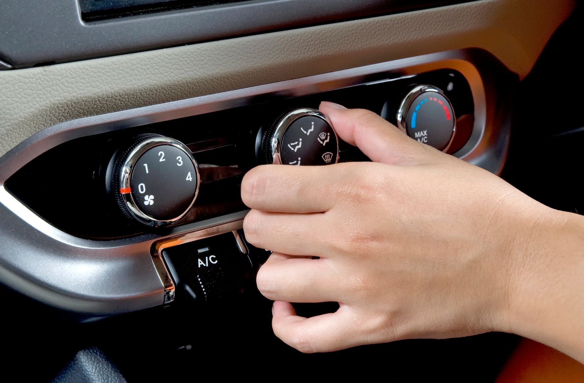 Ajustando manualmente el mando del climatizador del salpicadero de un coche con indicadores de temperatura azules y rojos.