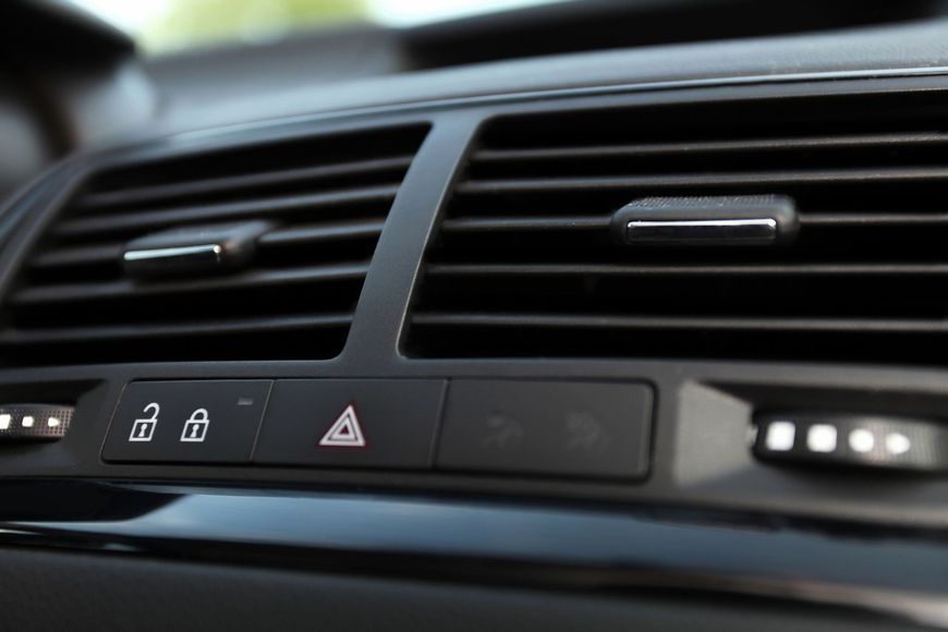Primer plano de la rejilla de ventilación del salpicadero de un coche y del panel de control