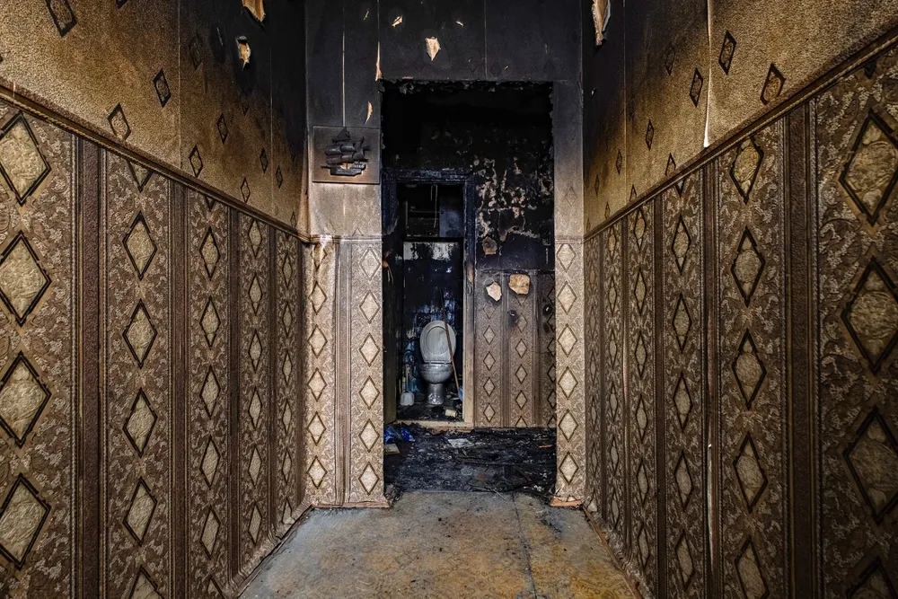 a dark hallway with a statue in the middle of it that has suffered fire damage