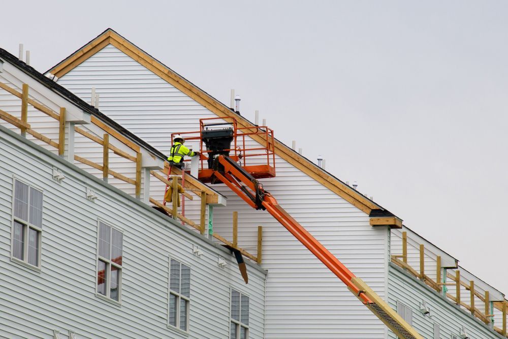 A man in a lift is working on the side of a building.