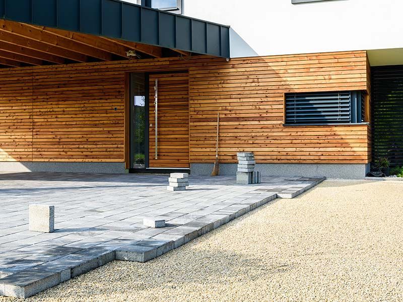 A house with a wooden siding and a concrete driveway in front of it.
