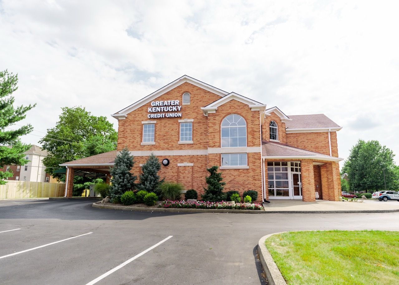 Brick building with Kentucky Retirement Systems sign. Exterior view, gray sky, parking lot.