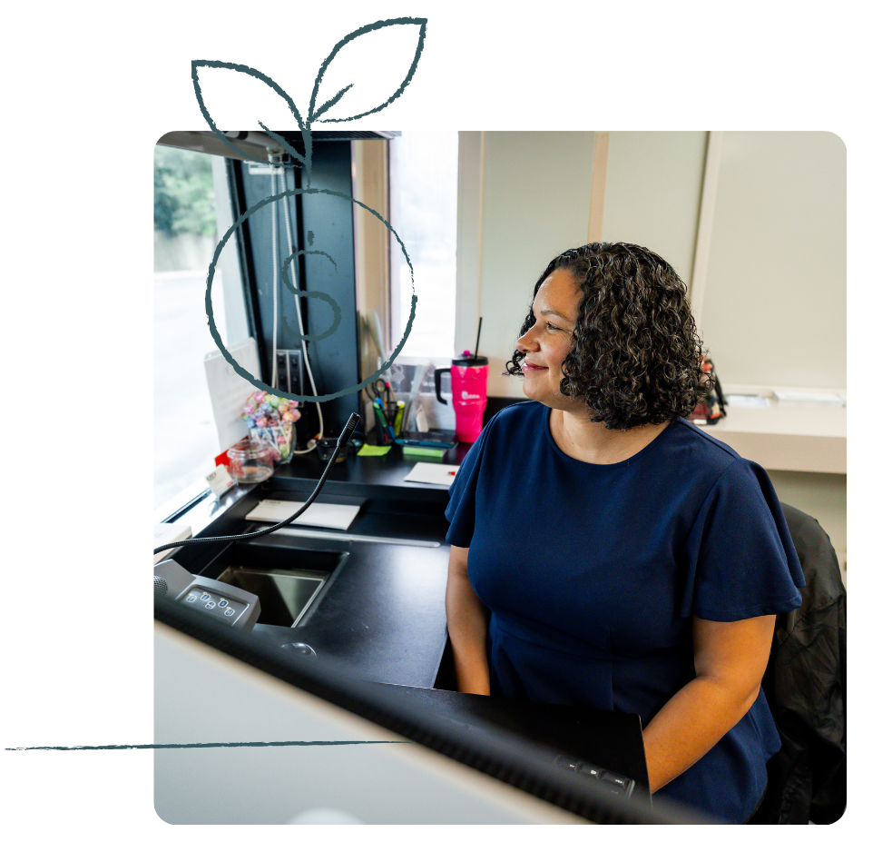 Woman in blue shirt at desk, looking out window.