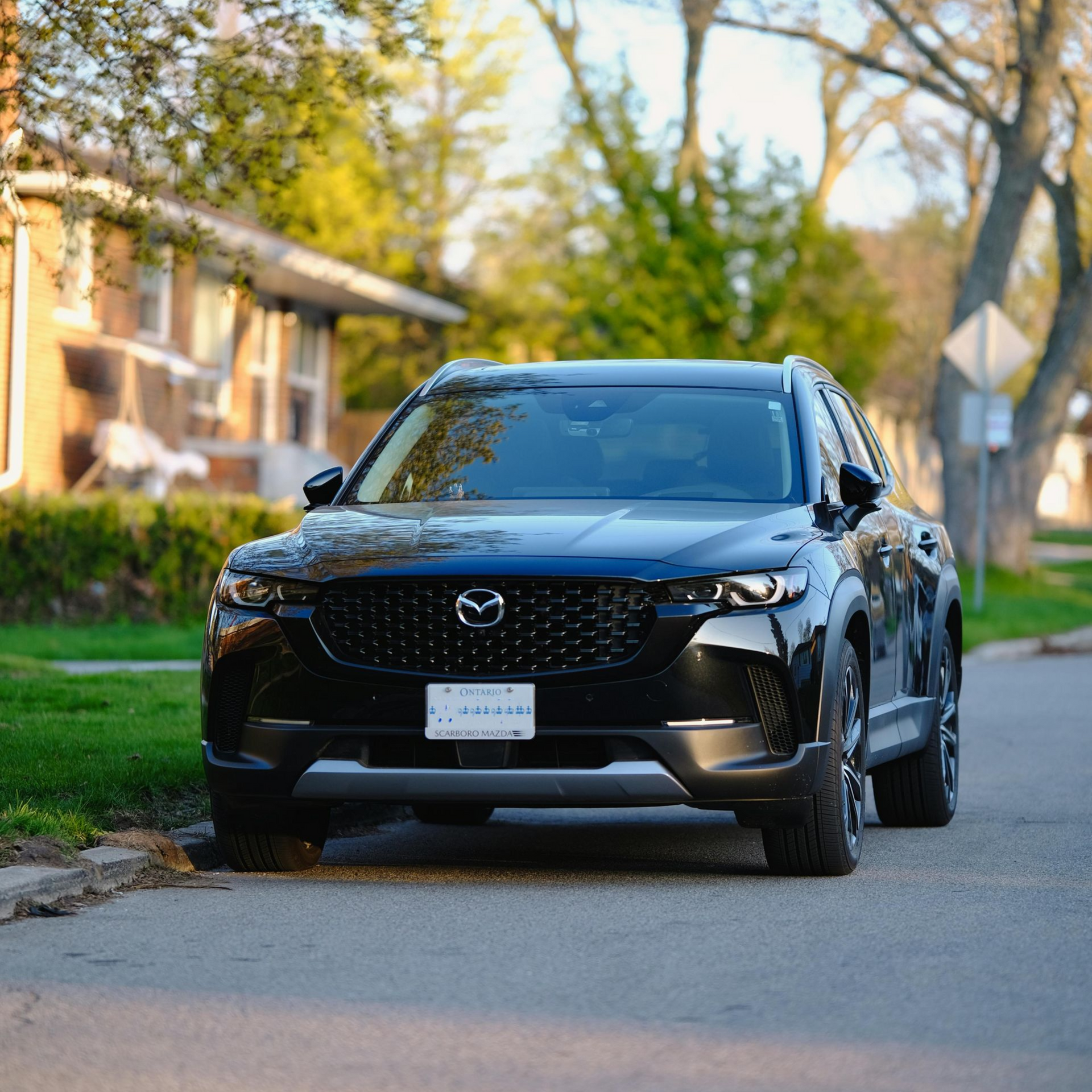 Black Mazda SUV parked on a residential street.