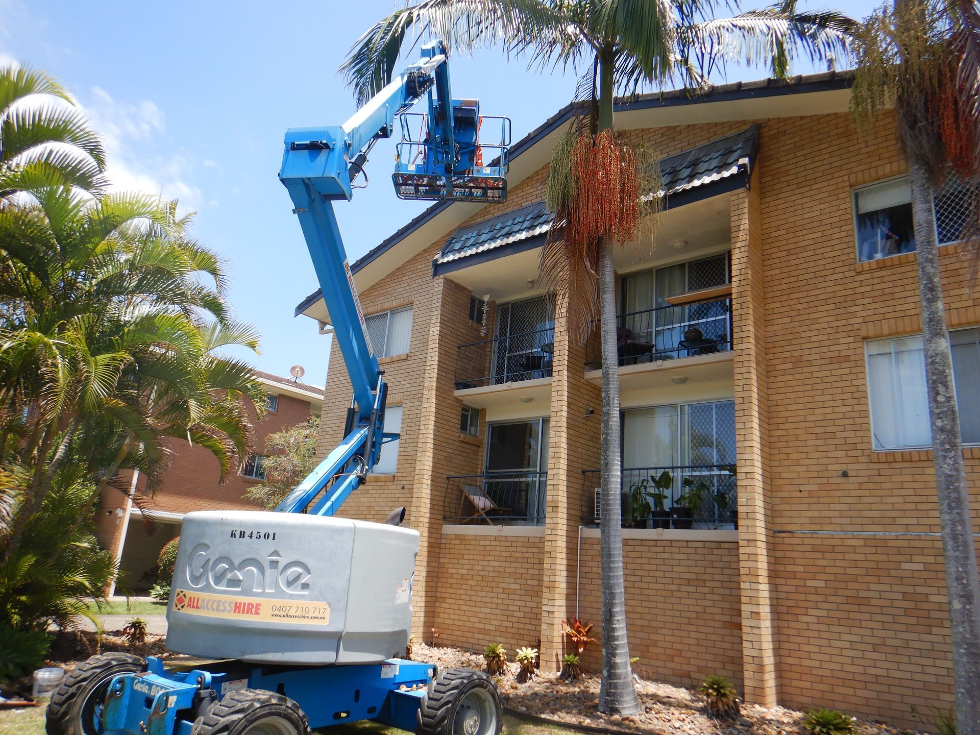 A Large Apartment Building With Balconies And Trees In Front Of It — Gold Coast Roof Repairs in Mudgeeraba, QLD