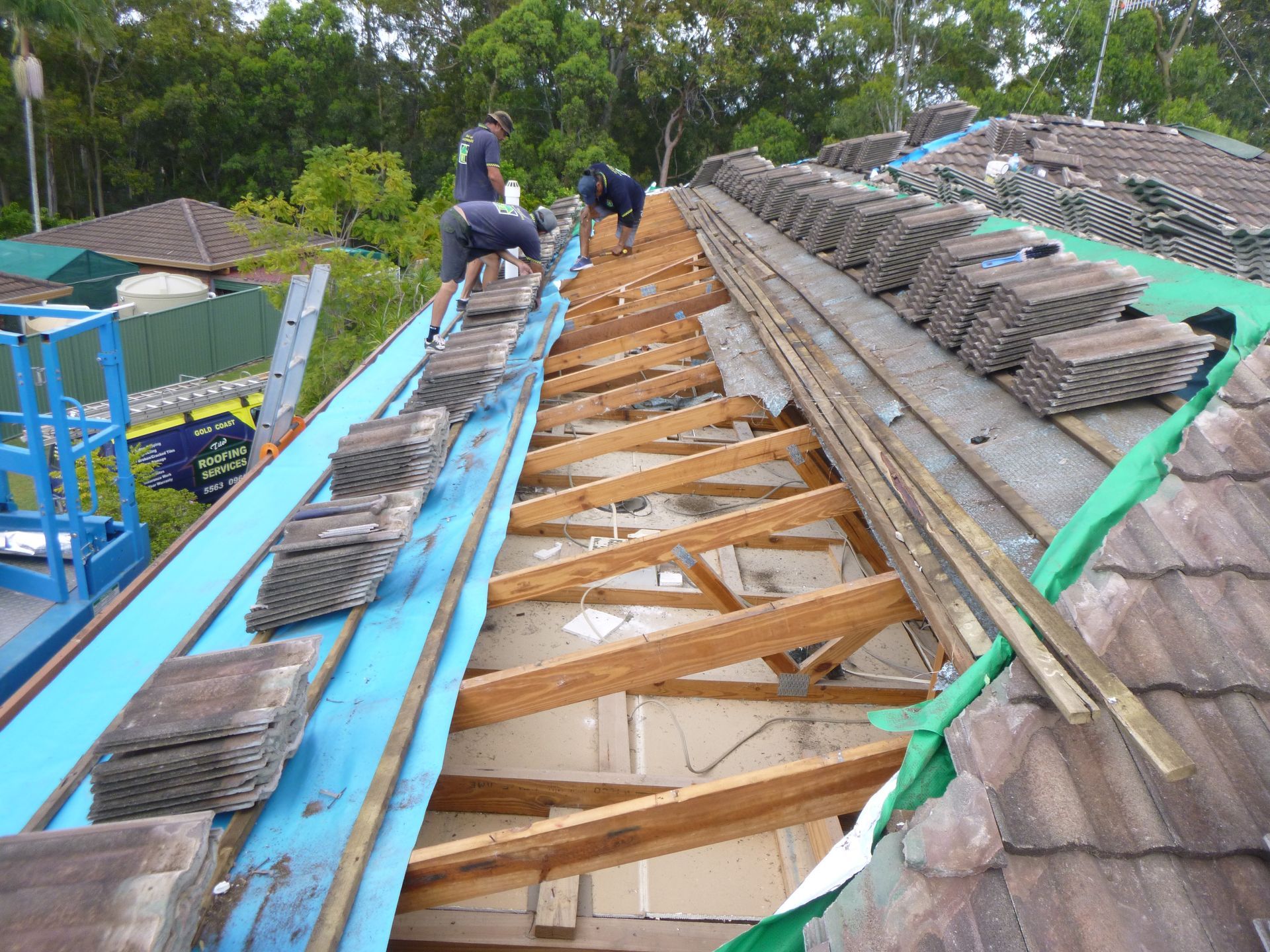 Two Men Are Working On The Roof Of A House — Gold Coast Roof Repairs in Mudgeeraba, QLD