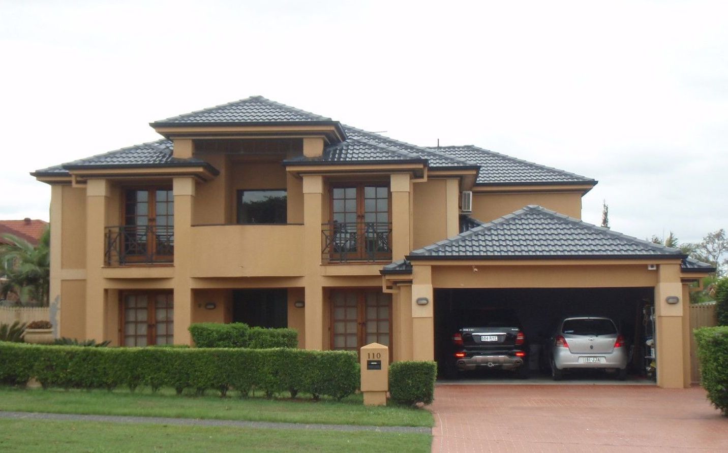 Two cars are parked in front of a large house
