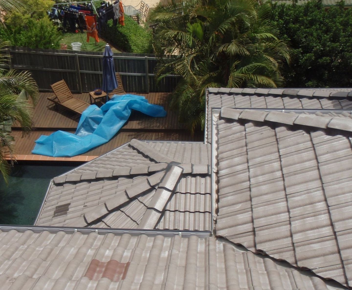 A roof with a blue tarp on it next to a pool