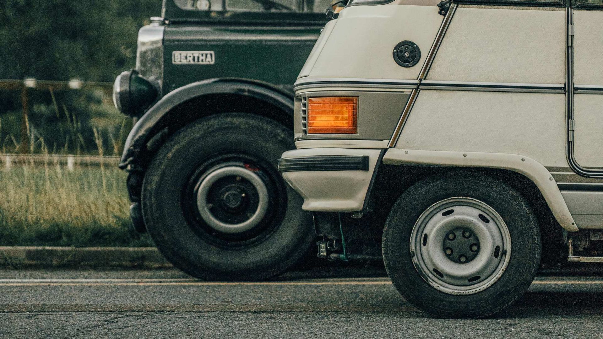 Two parked vans side by side, green and white, on a roadside.