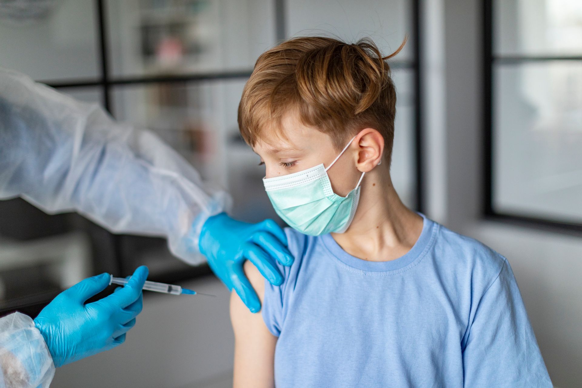 A young boy wearing a mask is getting a vaccine.