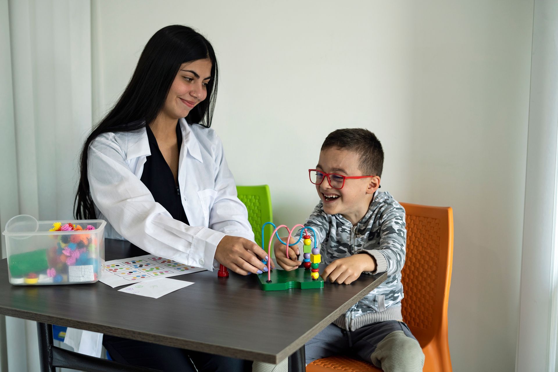 A woman is playing with a child at a table.