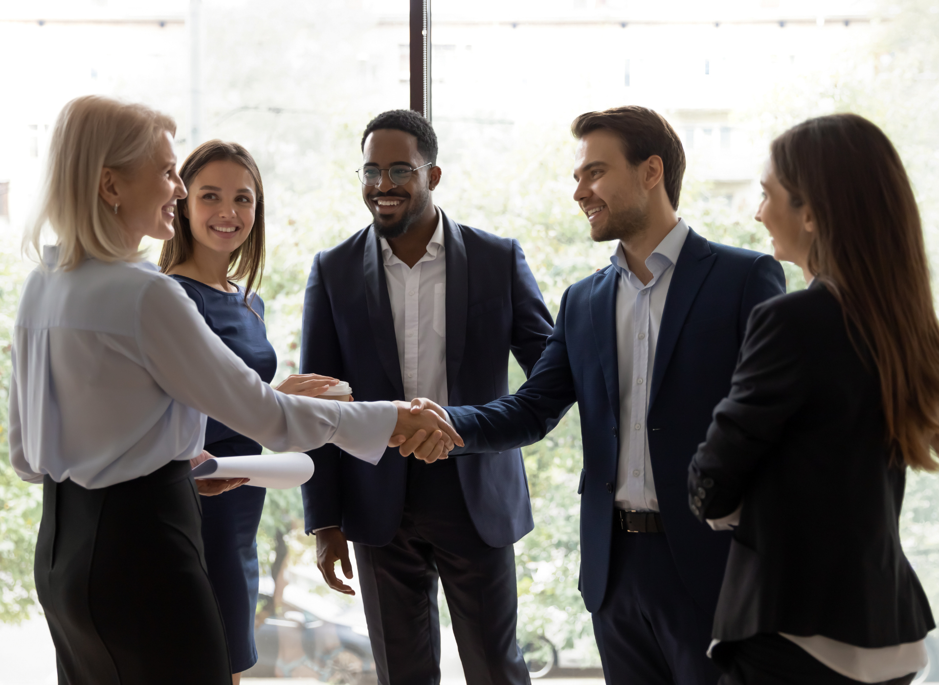 A group of business people are shaking hands in a room.