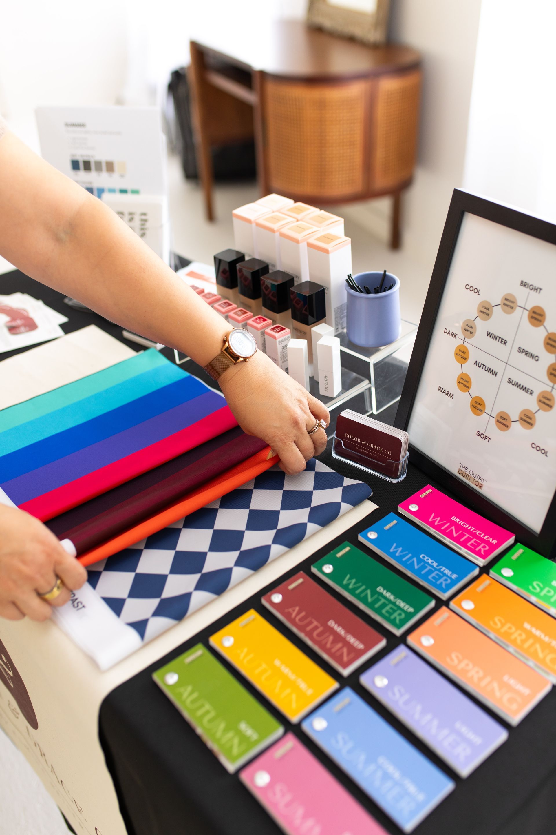 Person arranging colorful fabric and material samples on a table with labeled swatches and a color chart