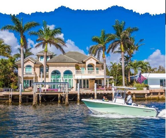 A boat in front of a large house with palm trees