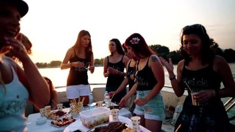 A group of women are standing around a table with food and drinks.
