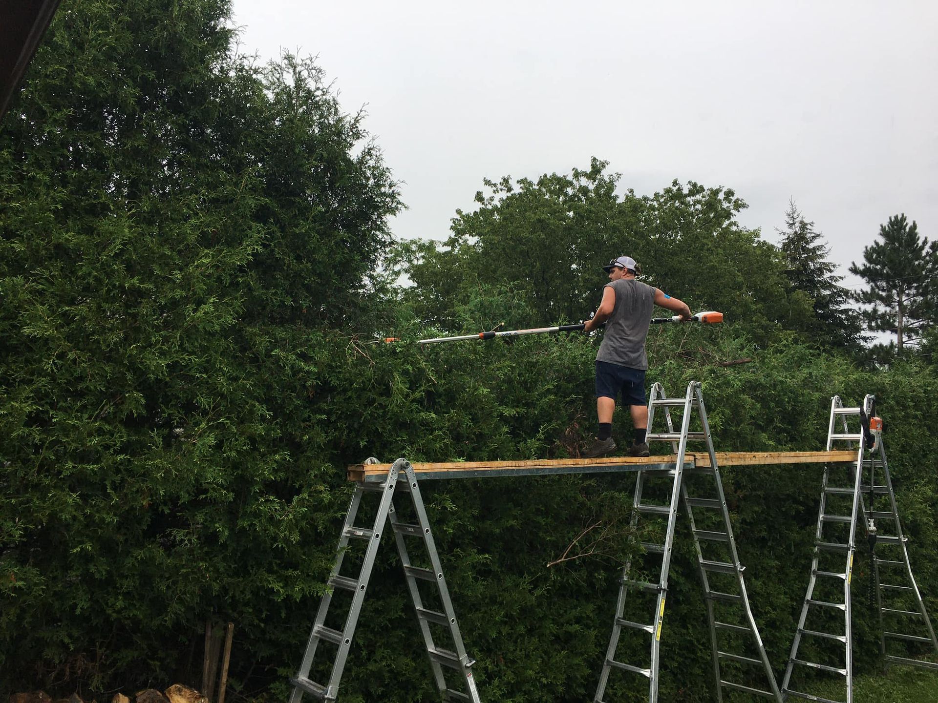 Un homme se tient debout sur une plate-forme en bois au sommet d'une échelle.