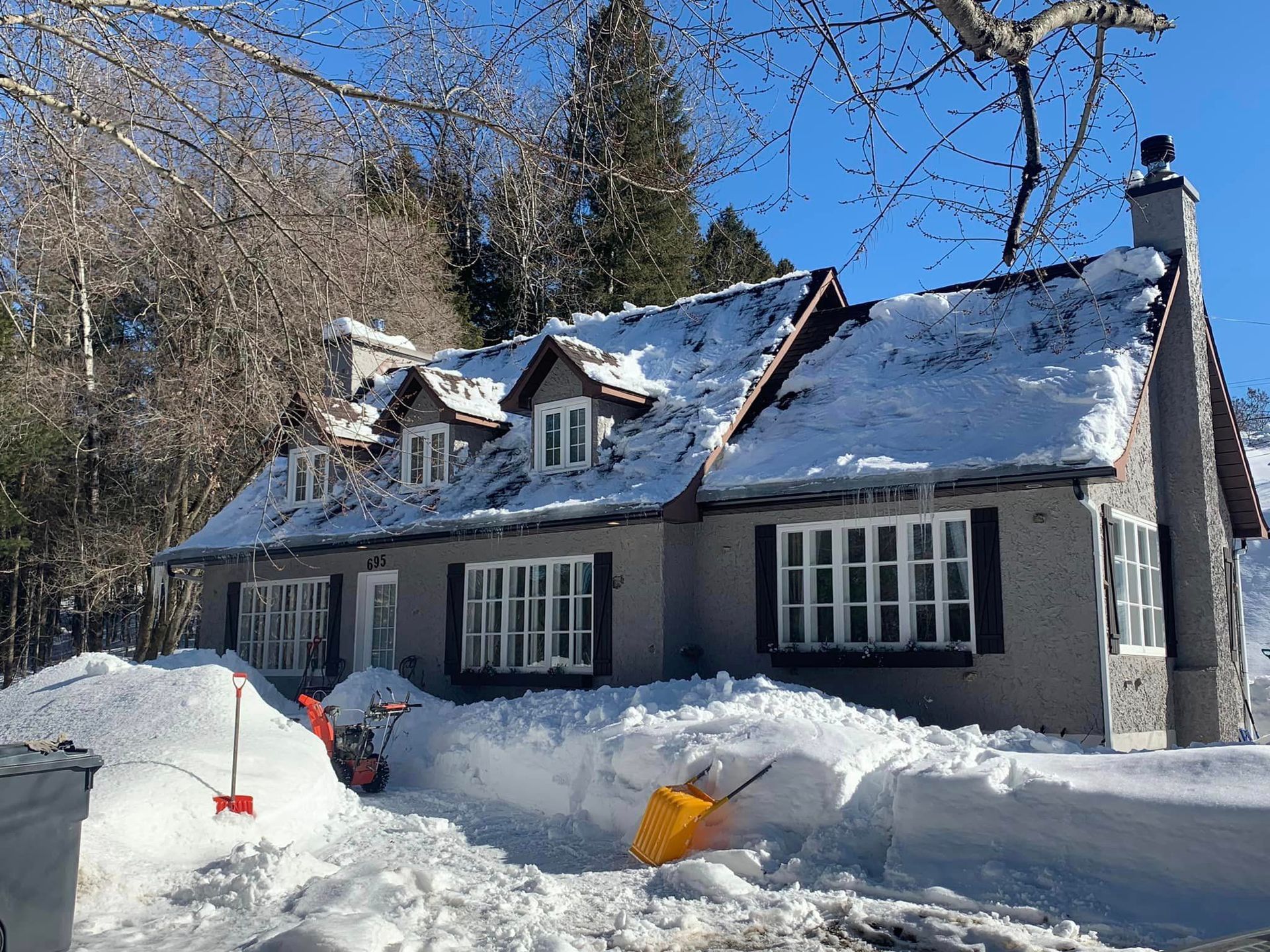 Une maison couverte de neige avec une pelle devant