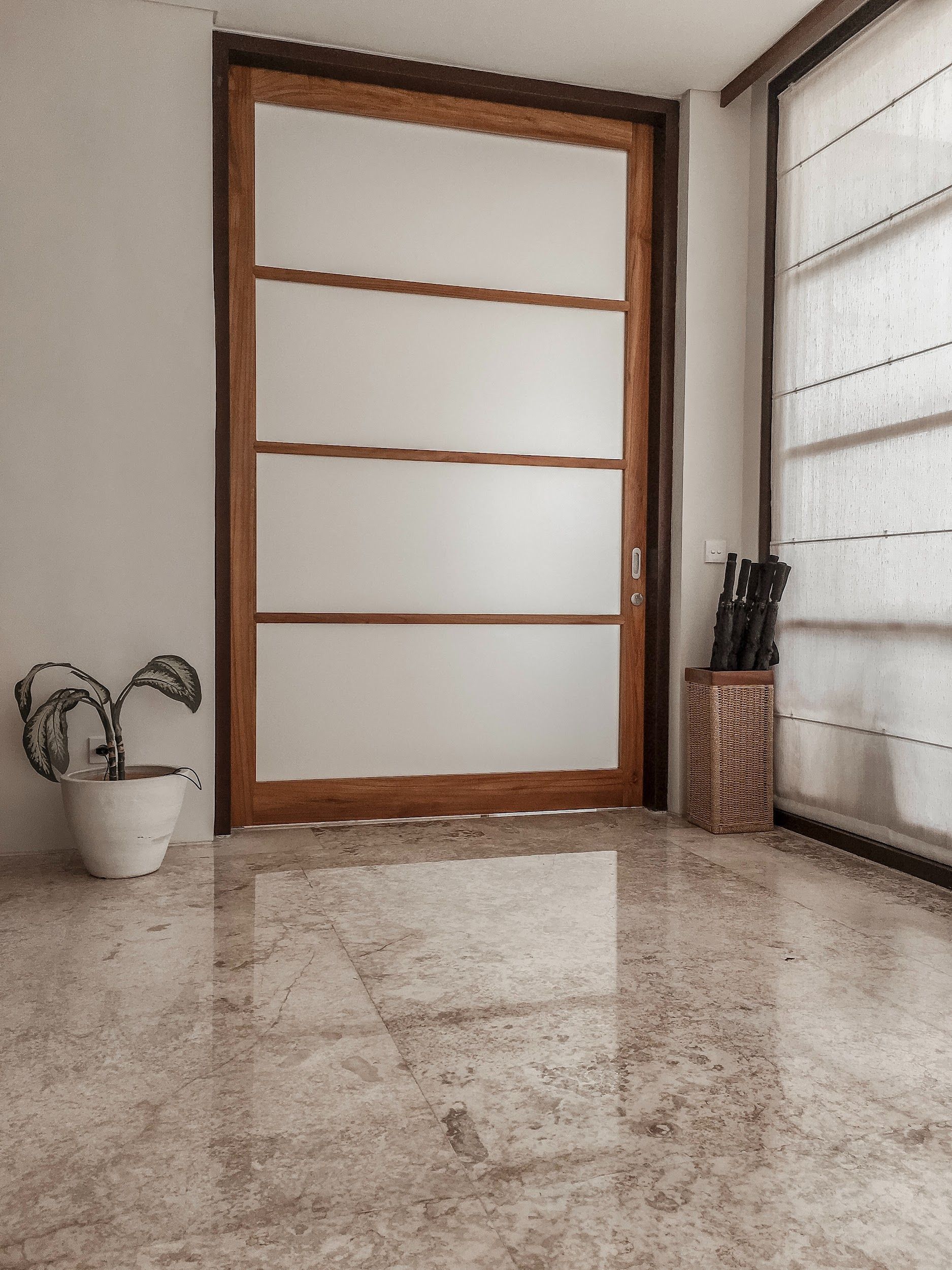 Wooden door with frosted glass panels, next to a window with blinds.