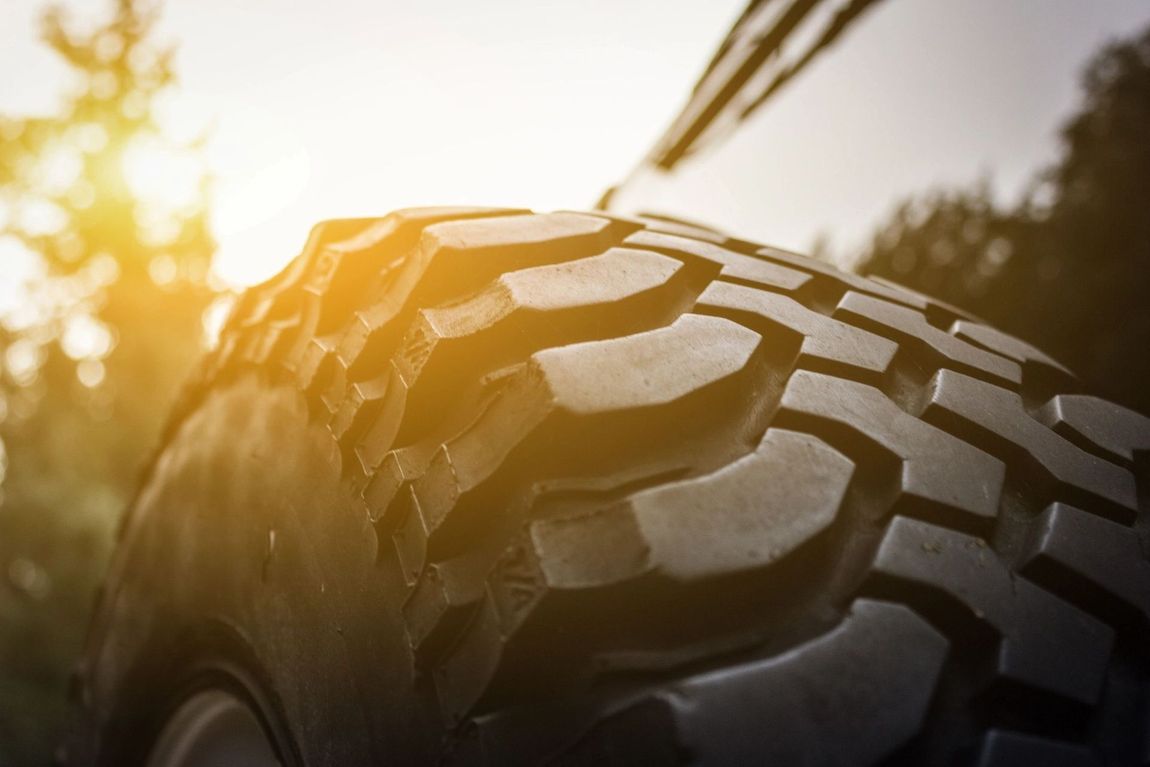 A close up of a tire on a car with the sun shining through it.