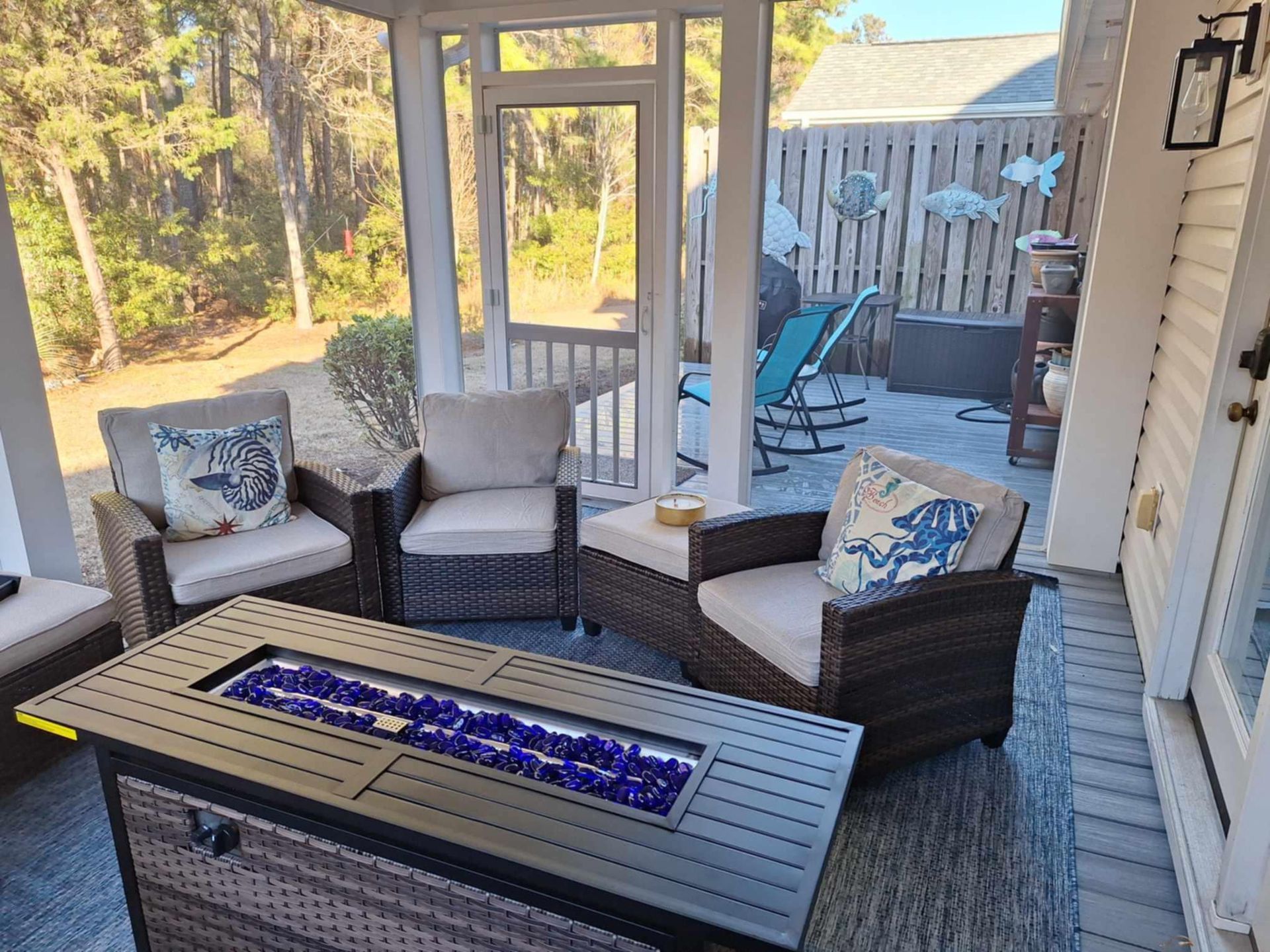 A screened in porch with wicker furniture and a fire pit.