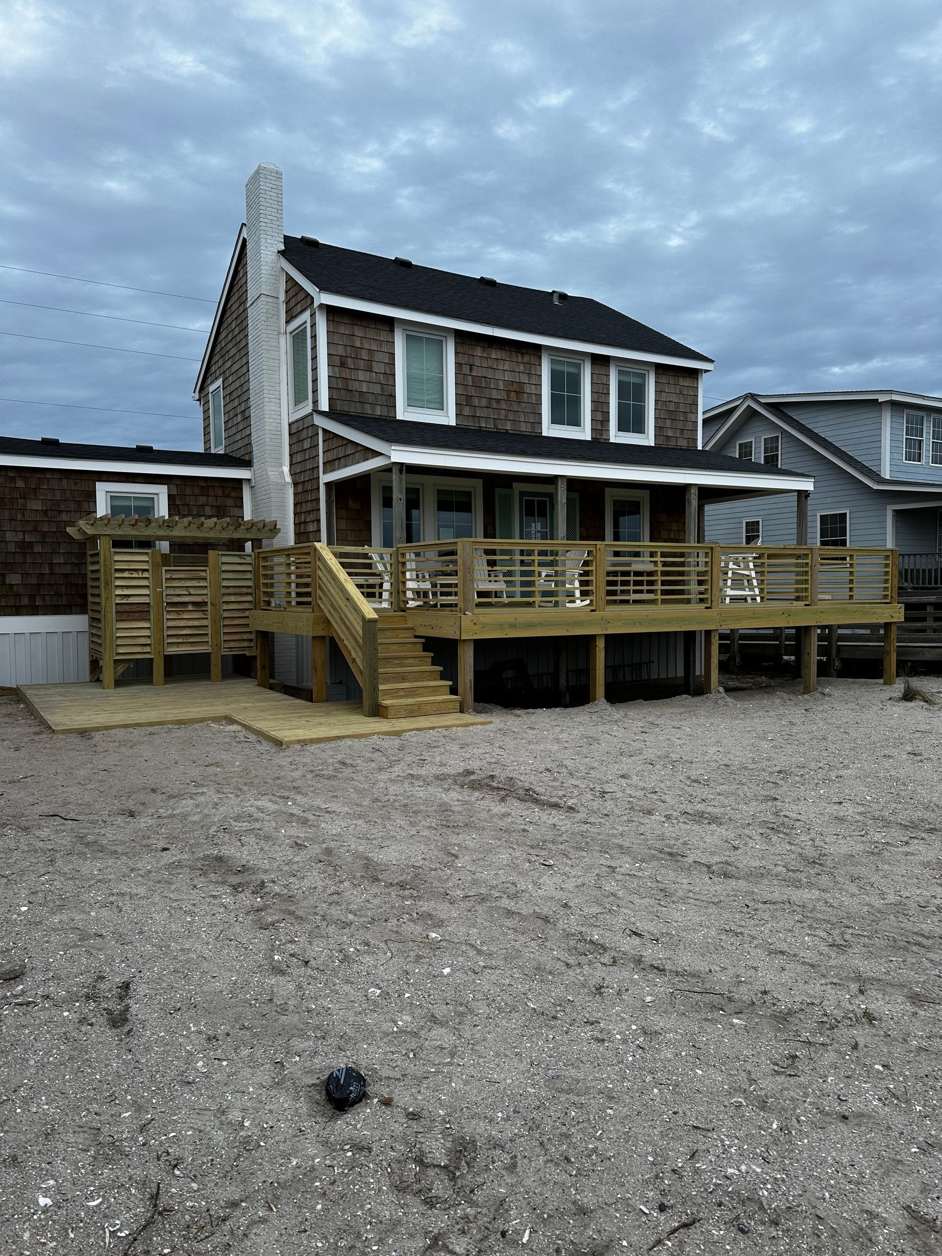 A house with a wooden deck on the beach.
