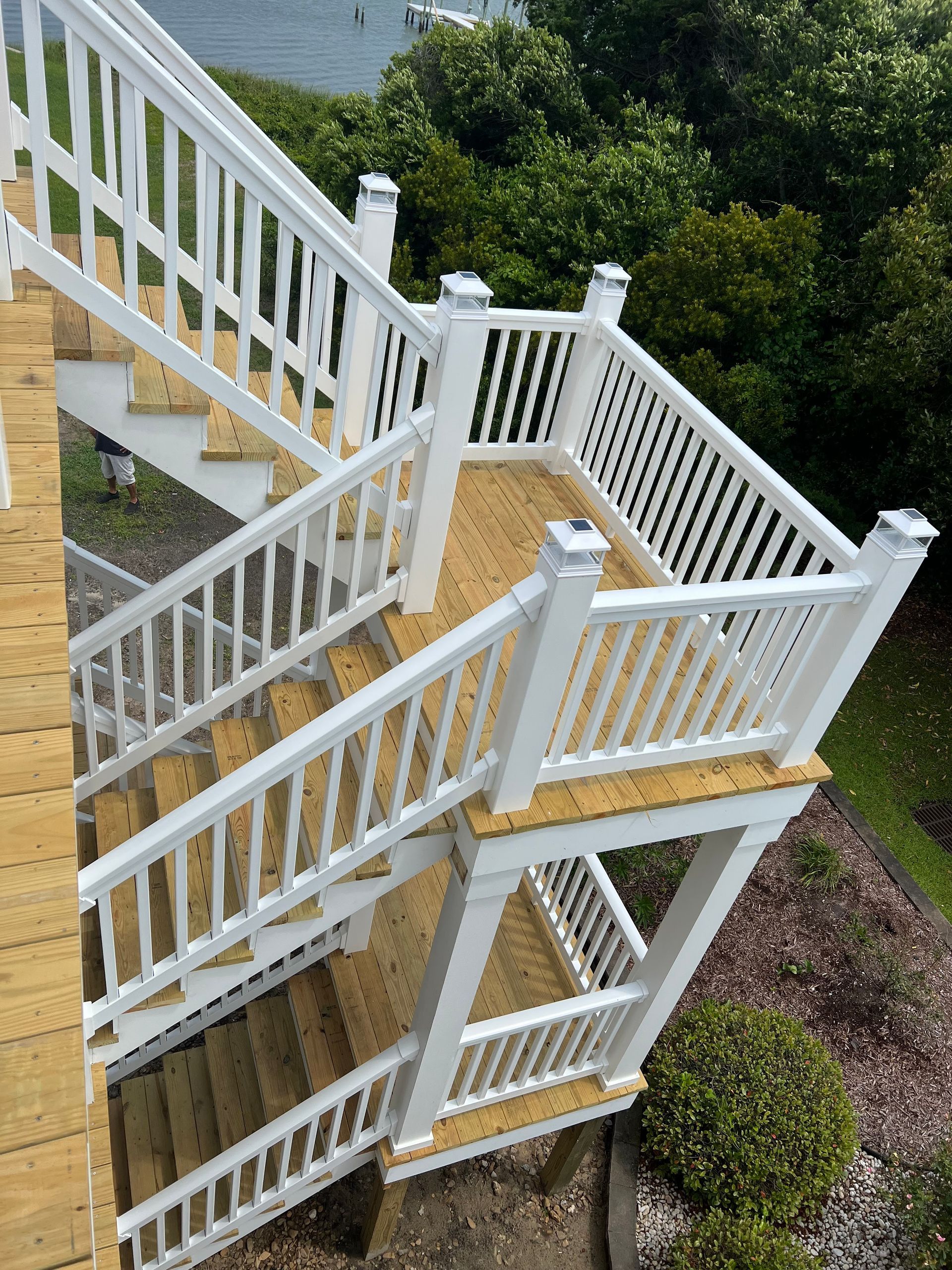 A set of stairs leading up to a deck with a white railing.