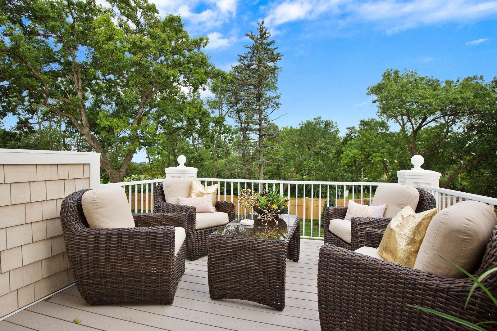 A balcony with chairs and a table with trees in the background
