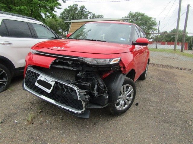 Red SUV with severe front-end damage parked in a lot beside a white vehicle.