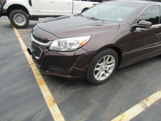 Brown sedan parked diagonally in a marked parking lot, with a white SUV in the background.
