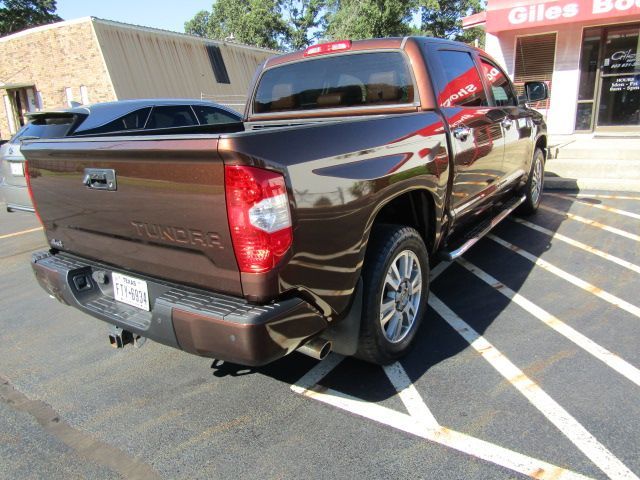 Brown pickup truck parked in a lot outside a store, rear three-quarter view