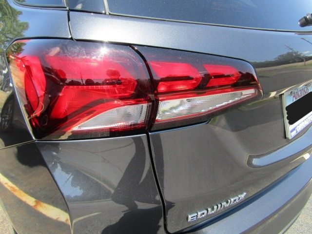 Close-up of a gray SUV’s red taillight and rear hatch badge.