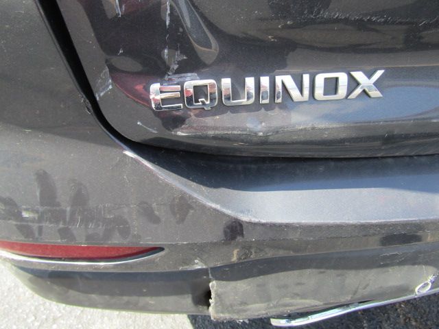 Close-up of a dusty black Equinox rear hatch with badge and scratched bumper step plate