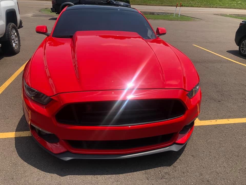 Red sports car parked in a lot, viewed from the front