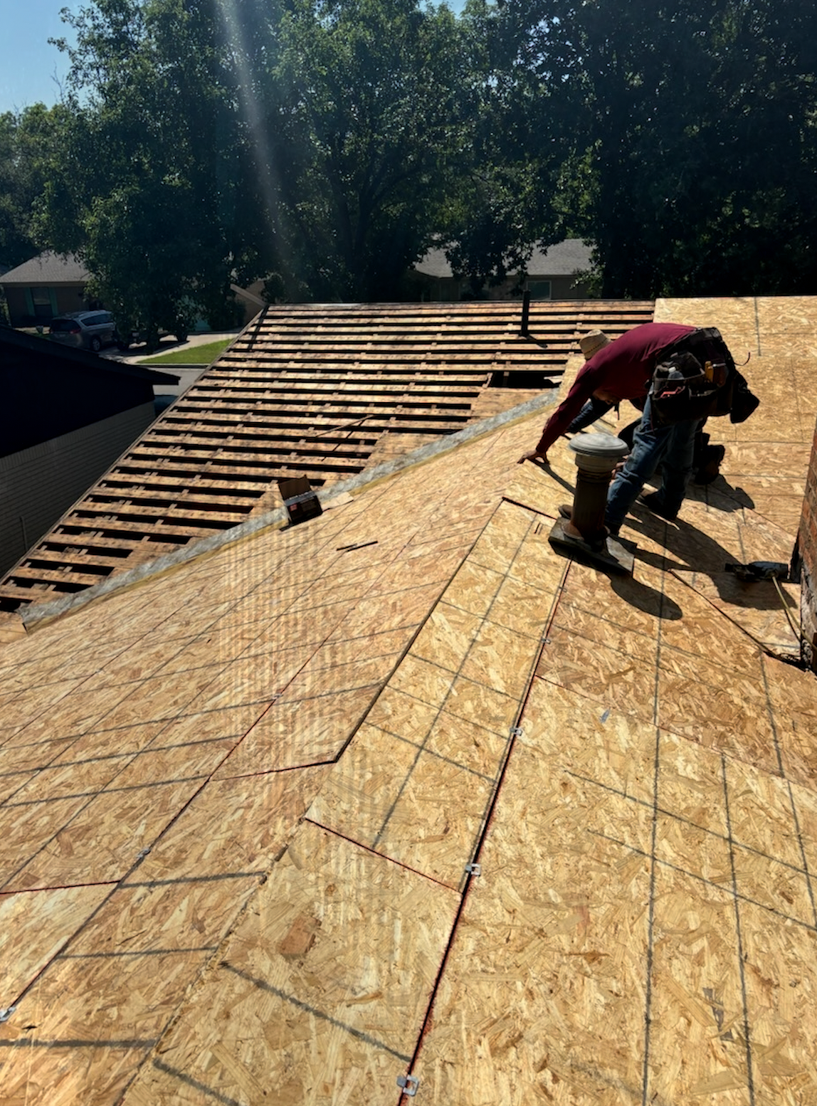 Roofers working on a residential roof, installing new plywood. Sunny day.