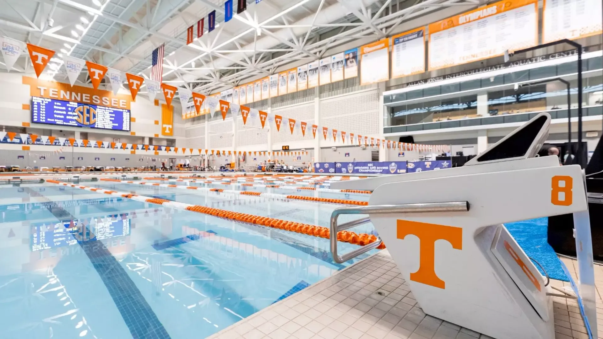 A large indoor swimming pool with a starting block with the letter t on it.