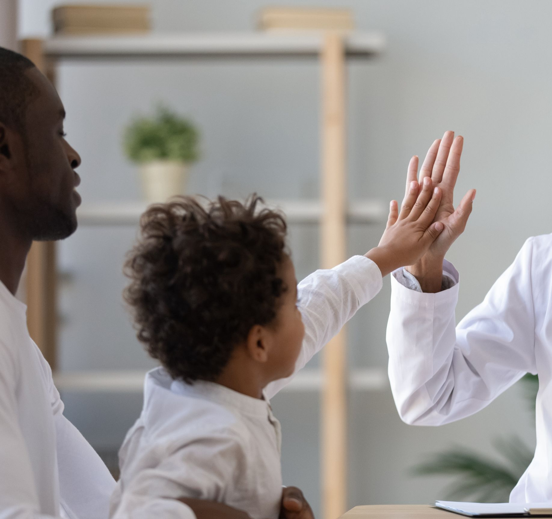 A person giving a high-five to a child in a doctor's office.