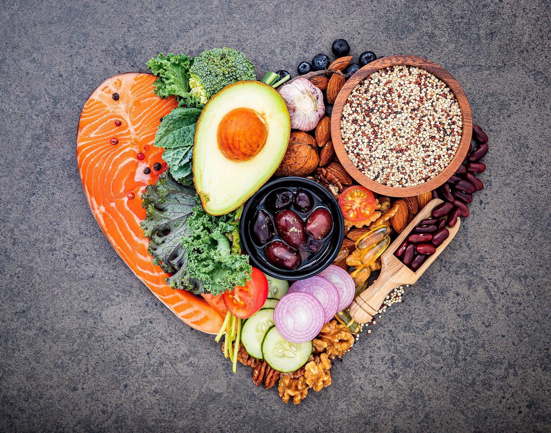Colorful assortment of salmon, avocado, berries, seeds, and vegetables on a gray background