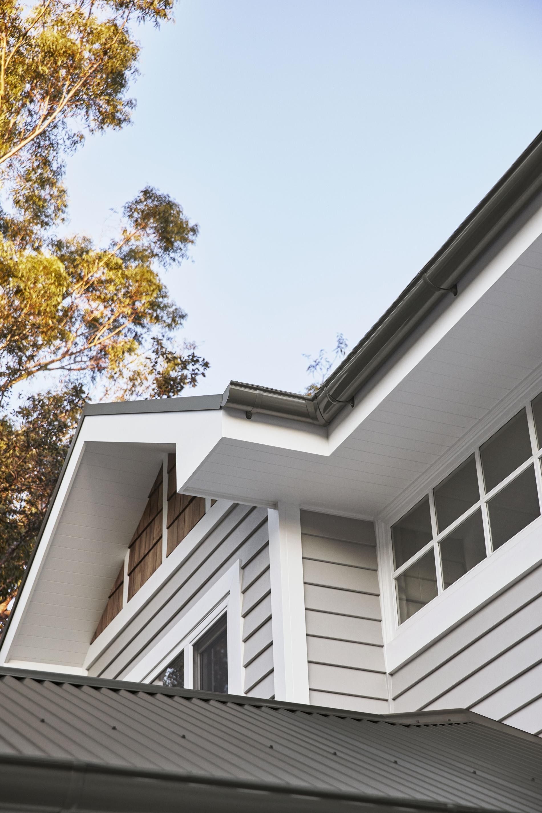 White house eaves and windows beneath autumn trees against a blue sky