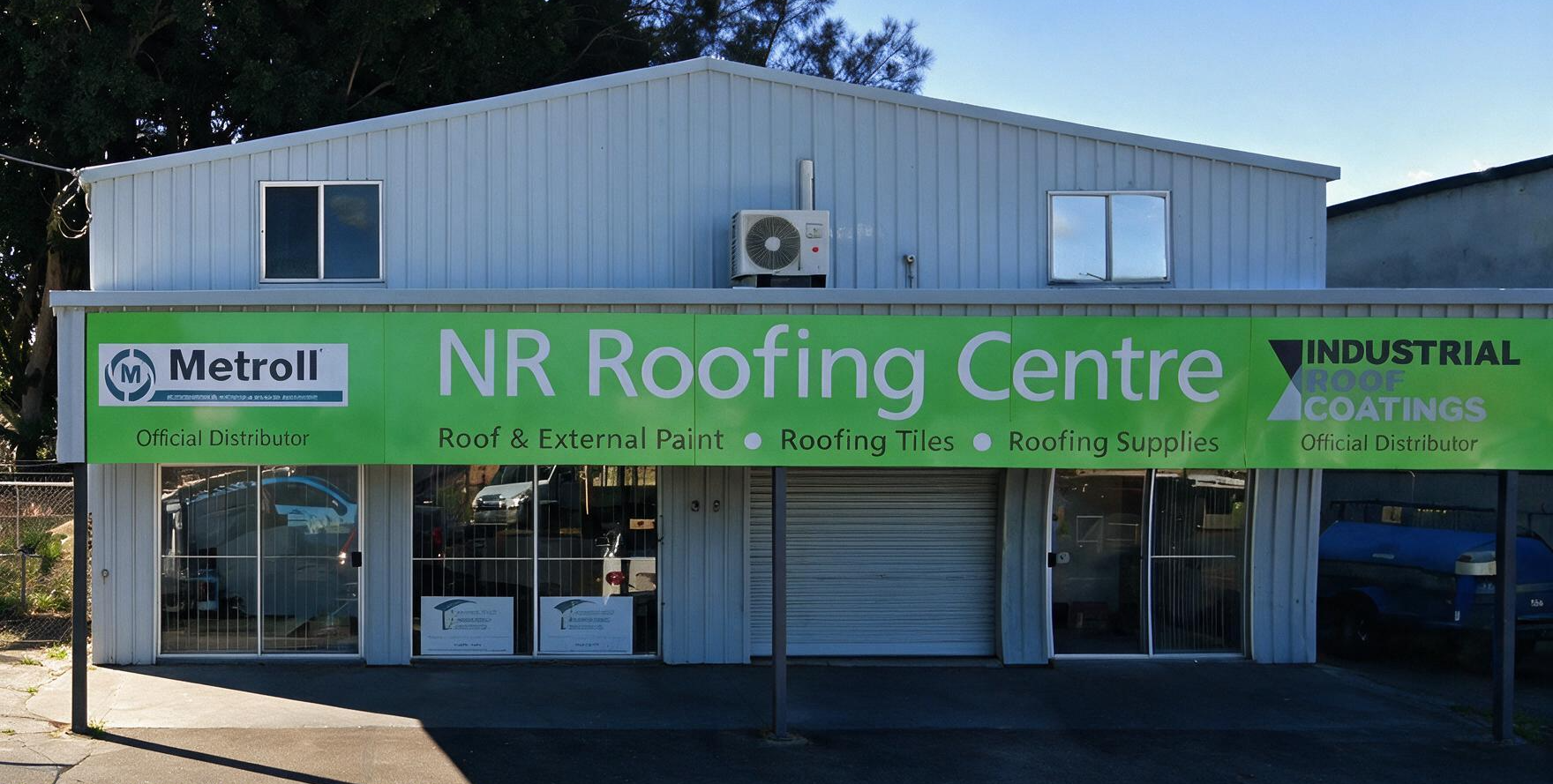 NR Roofing Centre storefront with green signage on a light blue industrial building