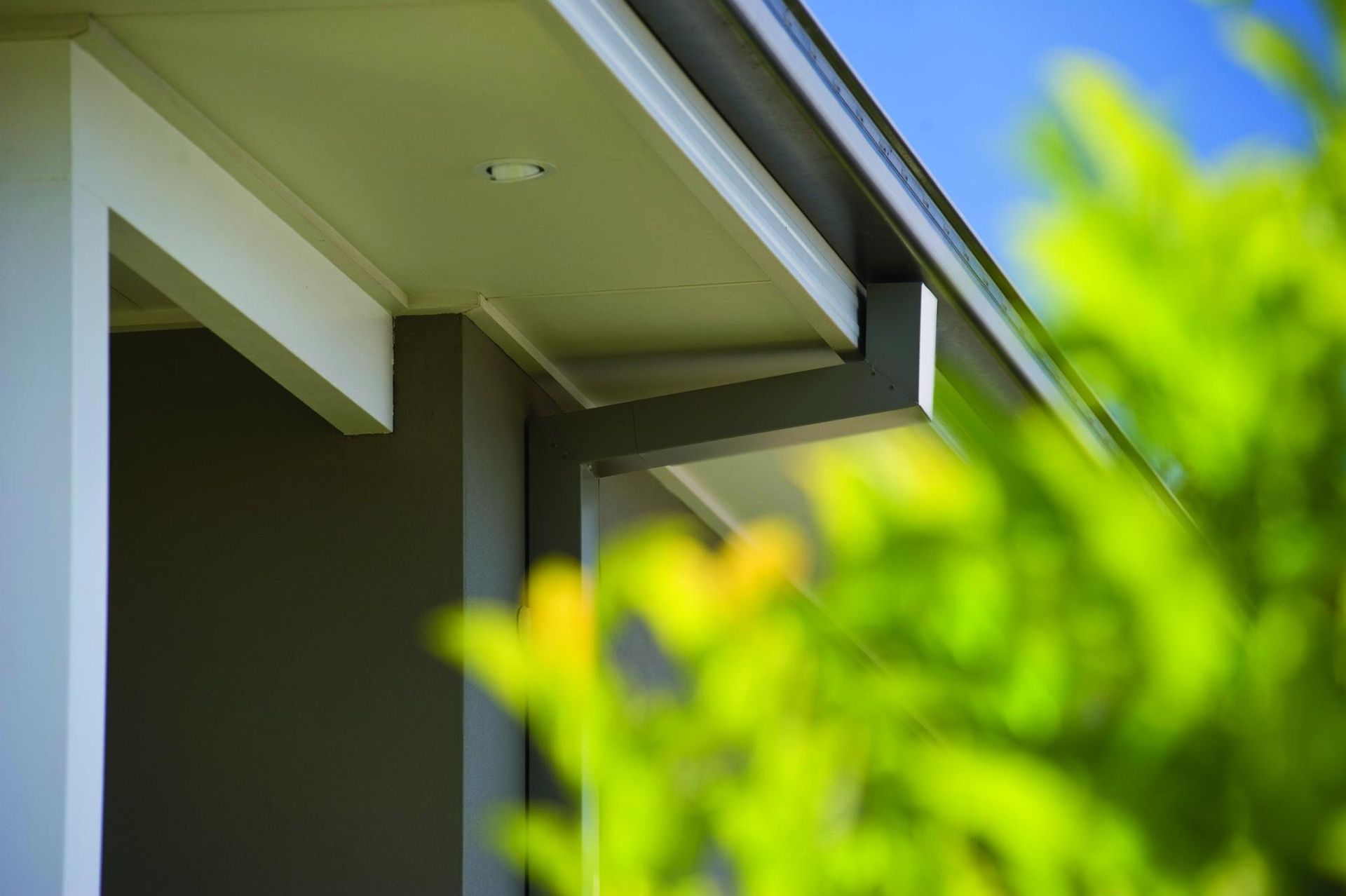 Close-up of a house roof eave with green foliage blurred in the foreground