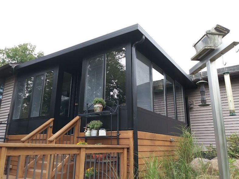 A house with a screened in porch and stairs leading up to it.