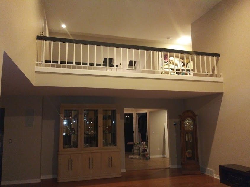 A living room with a balcony and a grandfather clock
