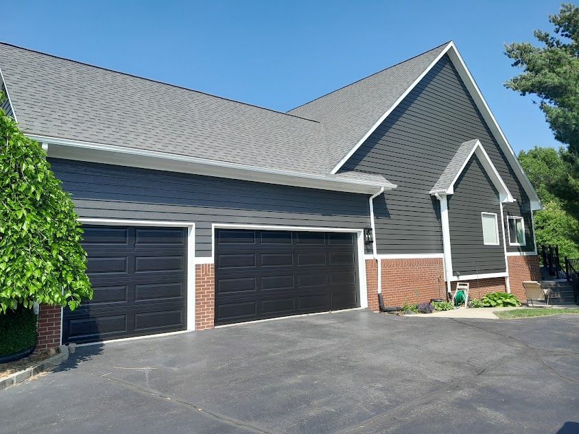 A large house with two black garage doors and a gray roof.