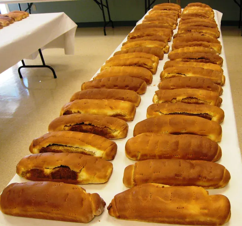 Rows of golden-brown loaves on a table in a bright room